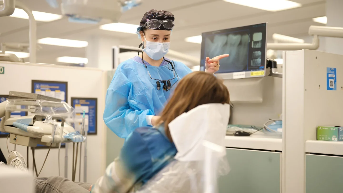 dental student pointing to x-ray, explaining it to patient