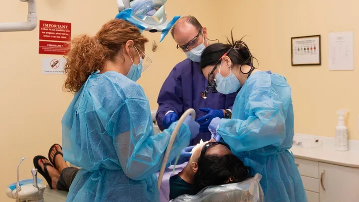 UCLA dental student in a clinical setting with preceptor and dental assistant.