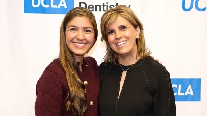 Two women smiling in front of a step and repeat