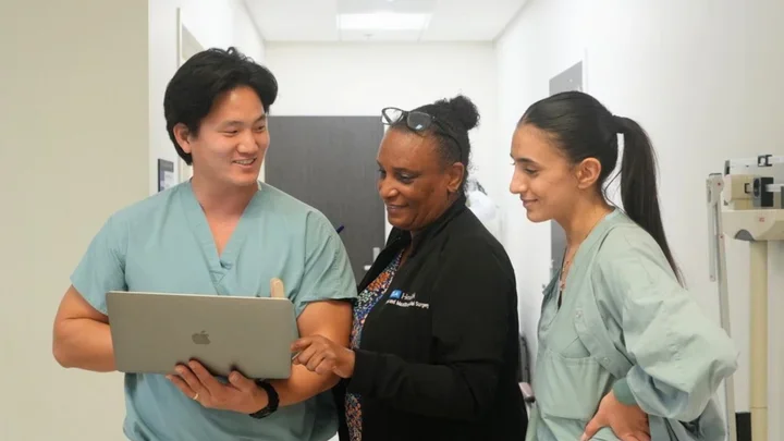 three people in medical attire. looking at a laptop