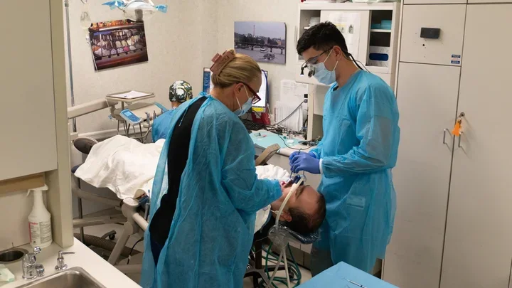 Two dentists working with a sedated patient