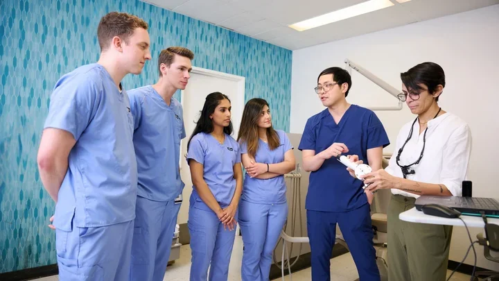 Four dental students listening to two faculty members