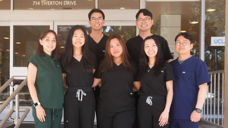 Group of six people in dental scrubs, standing on steps