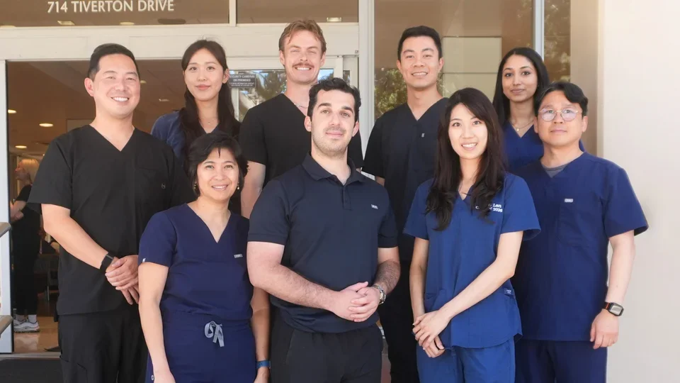 Group of nine people in dental scrubs, standing on steps