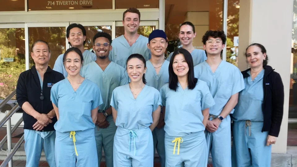 Group of 12 people in surgical scrubs, standing on steps