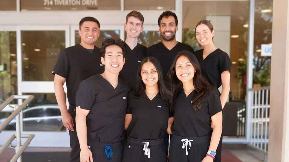 Seven people in matching black dental scrubs