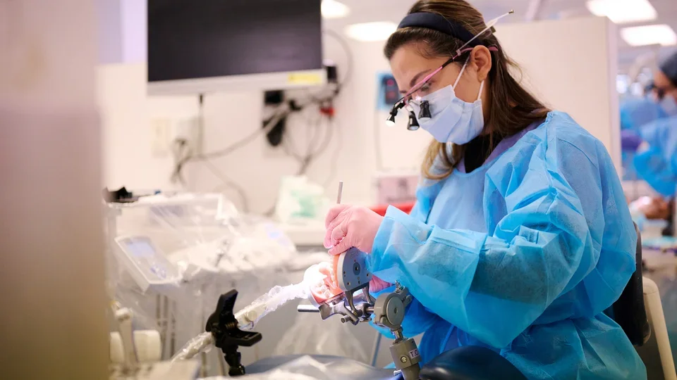 A dental student practicing with a dental practice model teeth.