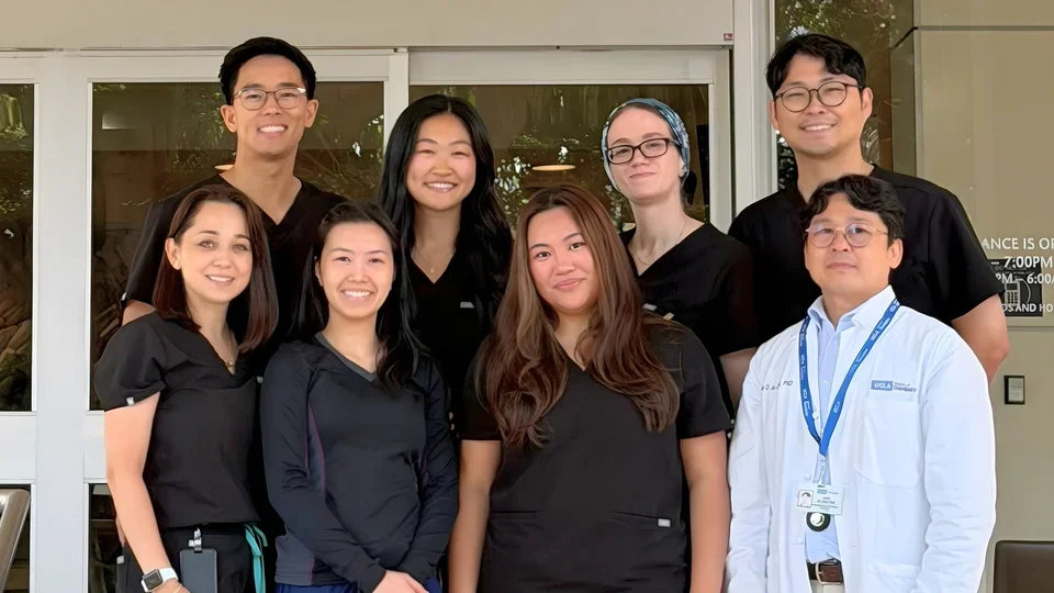 Group of seven people in dental scrubs, standing on steps