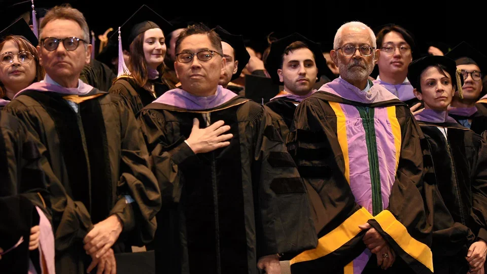 Faculty standing in the front row at the 2025 Commencement Ceremony.