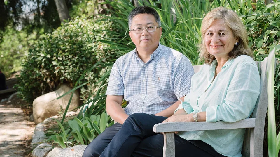 Faculty members sitting on bench in the botanical garden