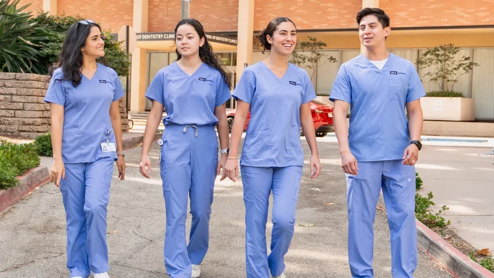 four students walking in blue scrubs