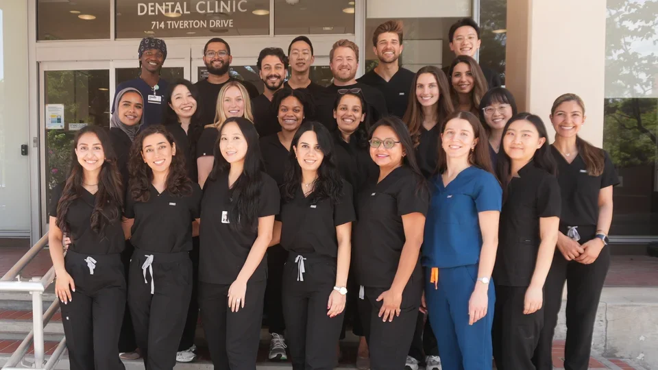 Group of 23 people in dental scrubs, standing on steps