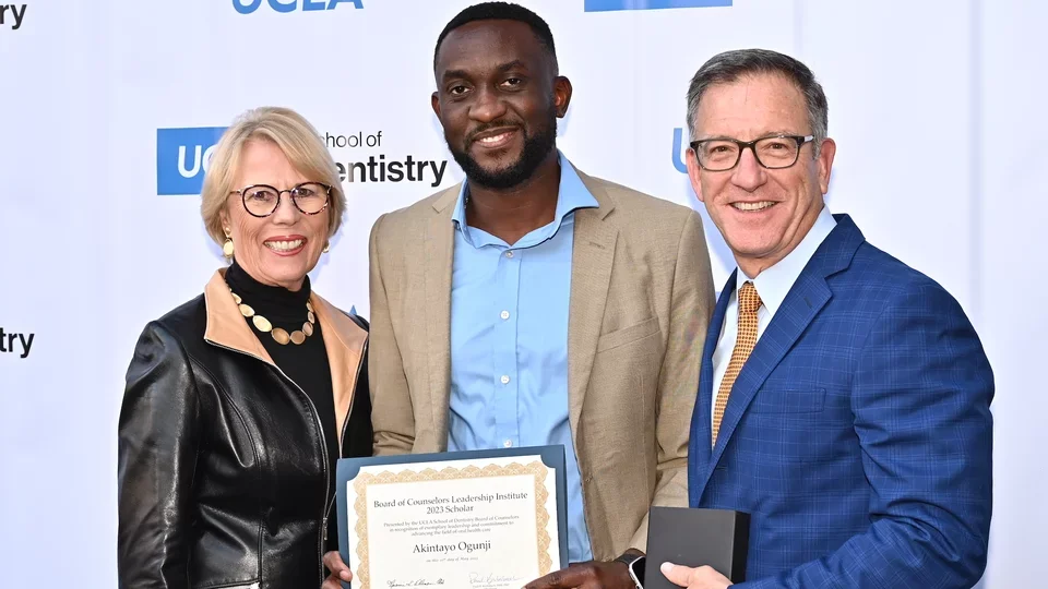 PPID scholar awardee and two colleagues in front of step-and-repeat