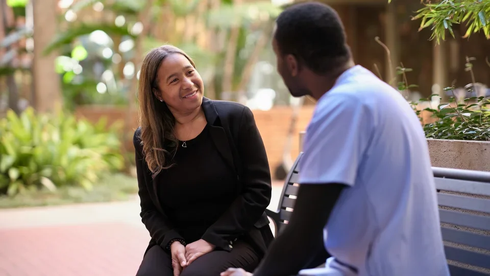 Woman smiling on bench, looking at man in dental scrubs
