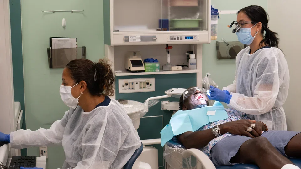 An Advanced Education in General Dentistry resident treats a patient while a dental assistant records the provided information.