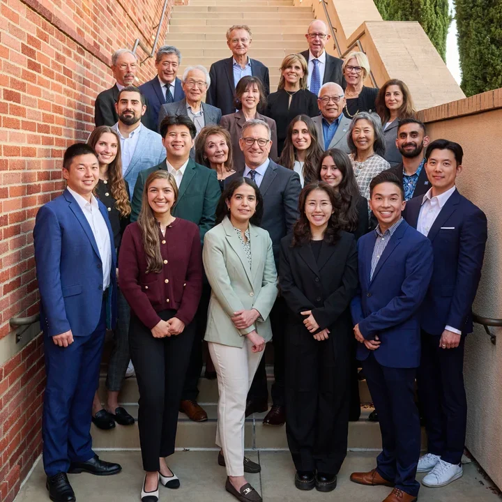 A photo of class of BOCLI 2025 cohort, the Board of Counselors, and Dean Paul Krebsbach poses on an outdoor staircase, dressed in business attire, smiling for a formal group photo