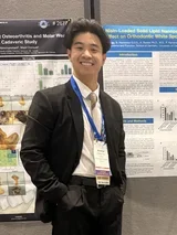 Andrew Tran posing with research poster