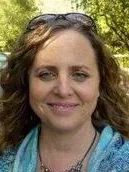 Robin Flint Macbride headshot wearing blue top, and outdoor background 