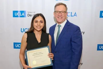 Paul Krebsbach, at left, presents an award to a dental student.