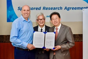 Three men smiling in front of a signed document