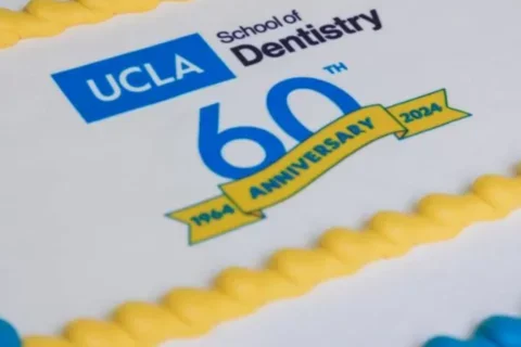 A blue, yellow, and white cake with the text "UCLA School of Dentistry 60th Anniversary 1964-2024"