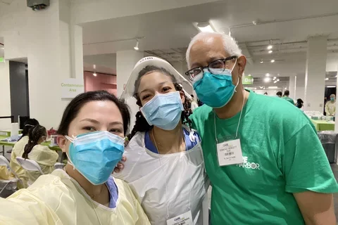 Two UCLA Dentistry students pose in masks with Dr. Edmond Hewlett, at right