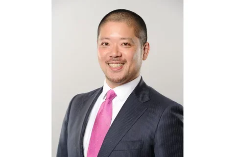                           Dr. Yusuke Hamada smiling, wearing a black suit with pink tie
