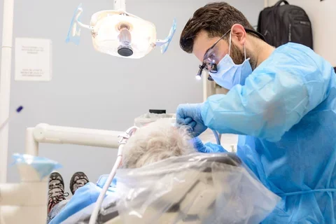 Dental student performing care on an elderly patient