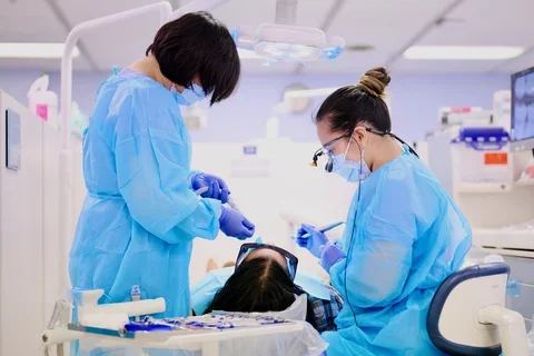 Two dentists in blue scrubs treating a patient