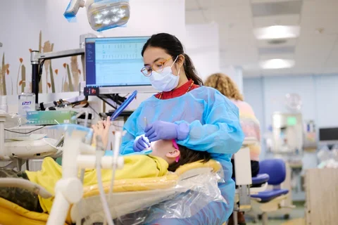 Dentist treating a child patient, who is holding a mirror