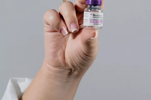 Botox vial held by a hand in a neutral setting