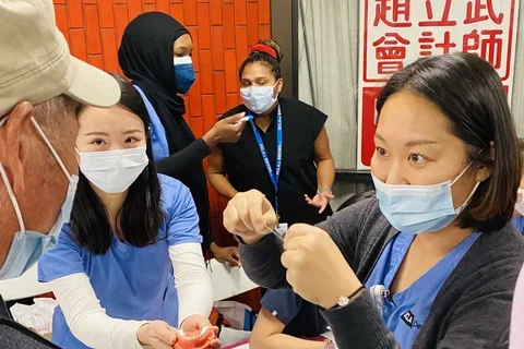 Dental students demonstrating flossing to elderly man