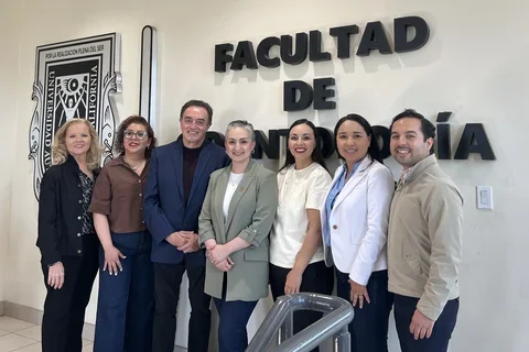 Seven people in front of sign reading "Faculdad de"