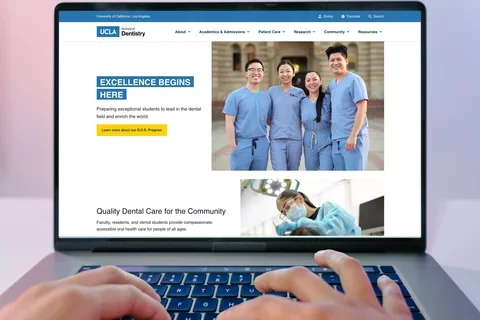 Person typing on a Macbook, viewing the UCLA School of Dentistry homepage