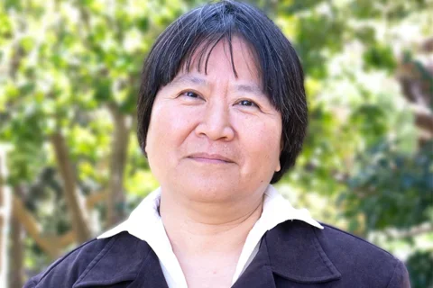 Dr. Yi-Ling Lin is wearing a blouse and a jacket in an outdoor setting.