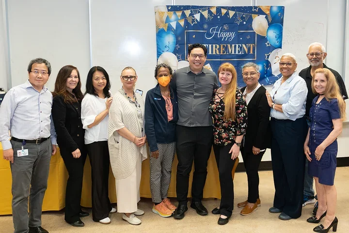 Ten people smiling in front of "Happy Retirement" banner