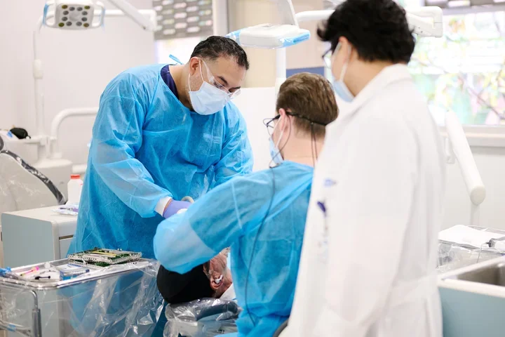 Dental Assistant in blue gown assisting with patient care.