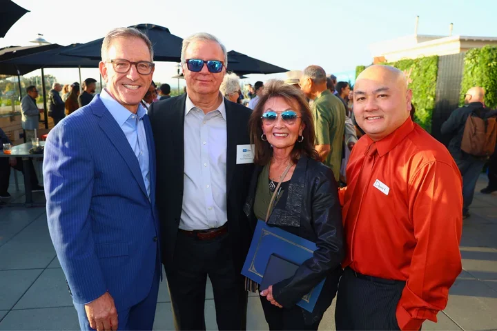 Group of four people. Woman third from left is holding a blue award folder