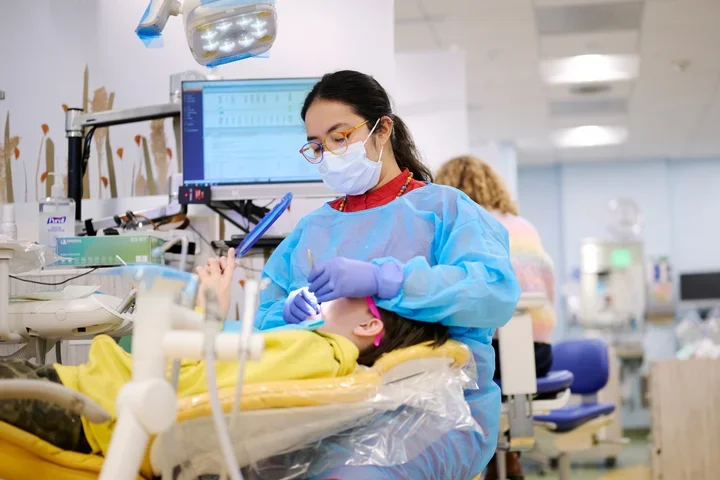 Dentist treating a child patient, who is holding a mirror