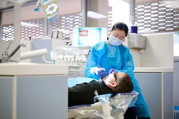 A dental resident performs a procedure on a patient.