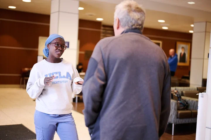 A dental student speaks with a patient in the clinic’s main waiting area.