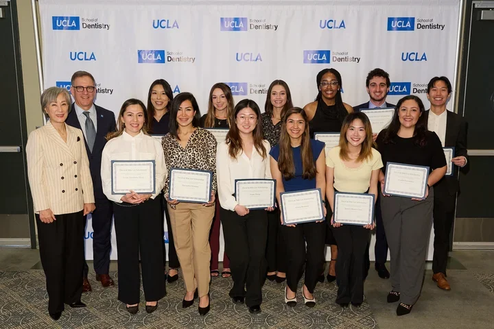 Group of 15 people smiling, many holding awards