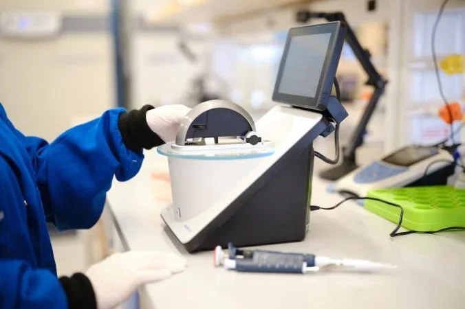 Hands using a nanodrop in a lab.