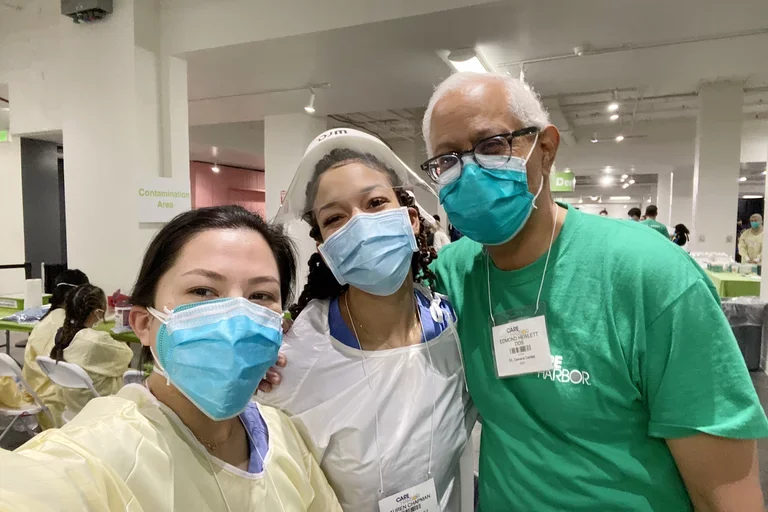 Two UCLA Dentistry students pose in masks with Dr. Edmond Hewlett, at right