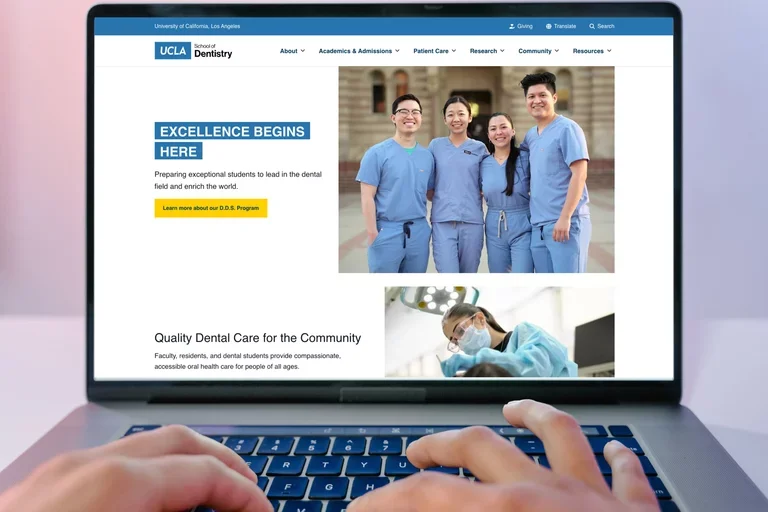 Person typing on a Macbook, viewing the UCLA School of Dentistry homepage