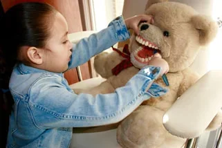 Child demonstrating how to floss teeth on a teddy bear