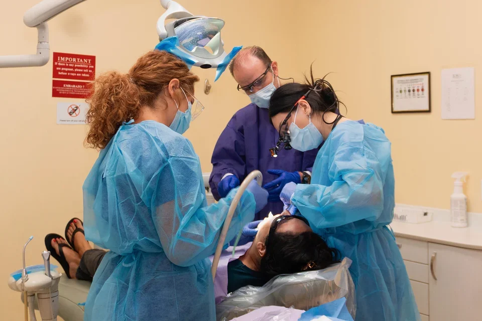 UCLA dental student in a clinical setting with preceptor and dental assistant.