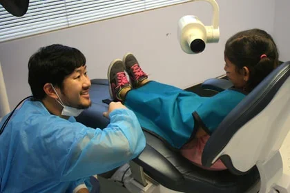 Dental provider smiling at child patient on dental chair 