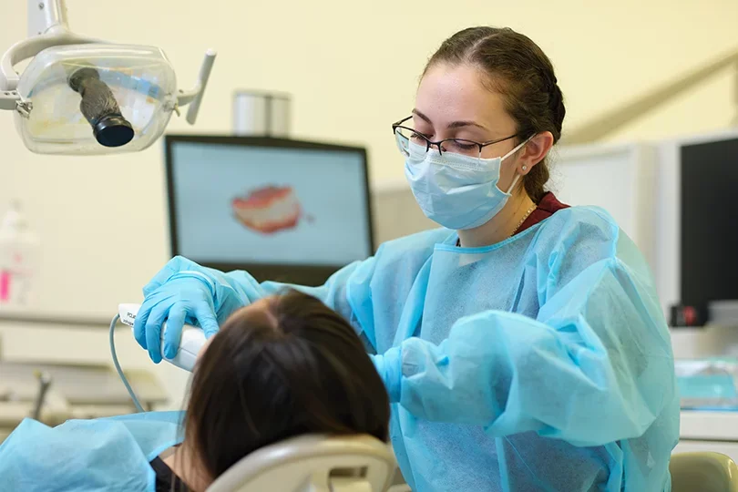 A dental student using a digital scanning tool on a patient.