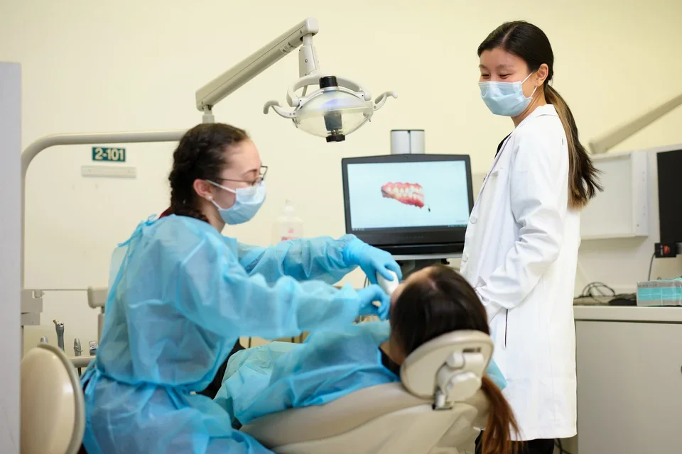 A dental student using digital technology to exam a patient.